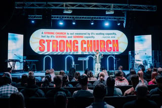 Stage backdrop with Pastor How's quote that a StronG Church is measured by serving and sending capacity, not seating capacity